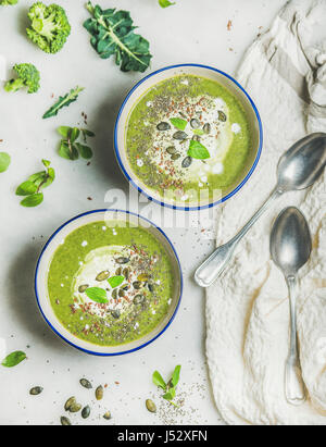 Frühling Detox grünen Brokkoli-Cremesuppe mit Minze und Kokosnuss Creme in Schalen in hellem Marmor Hintergrund, Ansicht von oben. Sauber, Essen, Diät, Vegan, Gemüse Stockfoto