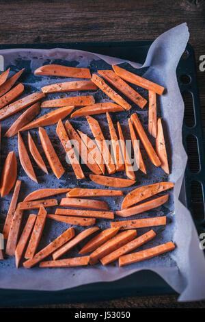 In Scheiben geschnitten Süßkartoffeln auf ein Backblech bereit, im Ofen gebraten Stockfoto