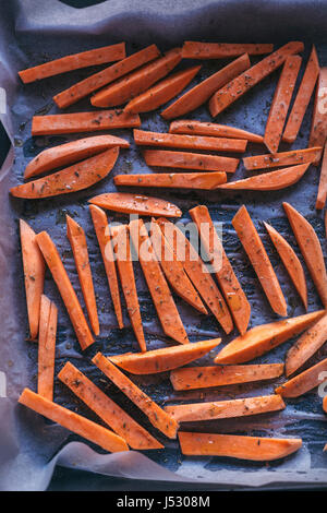 In Scheiben geschnitten Süßkartoffeln auf ein Backblech bereit, im Ofen gebraten Stockfoto