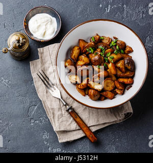 Geröstete Kartoffeln gebraten mit Steinpilzen in Schüssel auf Stein Hintergrund Stockfoto