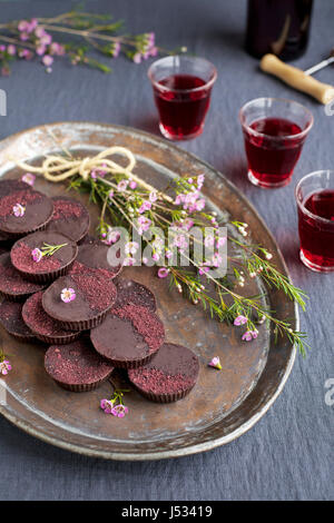 Marzipan-Hibiscus-Tassen serviert auf einem Kupfertablett mit Dessertwein. Phototgraphed auf eine graue Tischdecke. Stockfoto