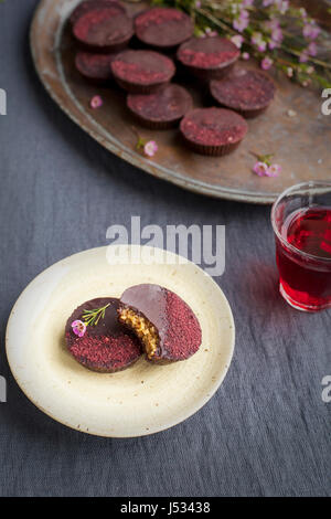 Marzipan-Hibiscus-Tassen serviert auf einem Kupfertablett mit Dessertwein. Phototgraphed auf eine graue Tischdecke. Stockfoto