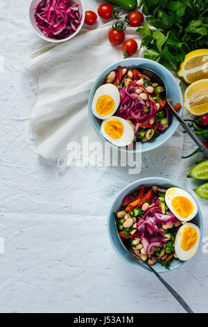 Türkische würziger Bohnensalat, bekannt als Piyaz in Schalen mit halbierten hartgekochten Eiern auf der Oberseite, begleitet von Sumach, roten Zwiebeln, Paprika, grüne Zwiebel serviert Stockfoto