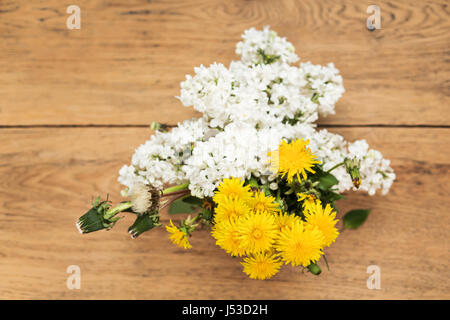 Bouquet von blühenden weißen lila und gelbe Löwenzahn mit Laub auf einem alten Holztisch, Ansicht von oben Stockfoto