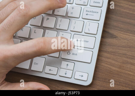 Mannes Hand drücken enter-Taste Wireless-Tastatur auf dem Holztisch Stockfoto