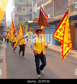 KAOHSIUNG, TAIWAN--16. März 2014: religiöse Anhänger in gelben Westen tragen Fahnen in einer Prozession, die Teil einer lokalen religiösen Zeremonie ist. Stockfoto