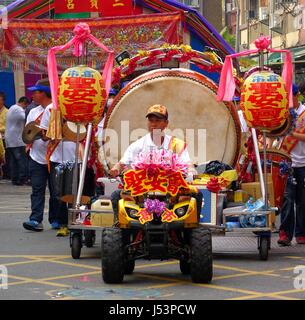 KAOHSIUNG, TAIWAN--16. März 2014: ein unbekannter Mann fährt einen kleinen Traktor, die eine große zeremonielle Trommel als Teil einer lokalen religiösen Ceremo zieht Stockfoto