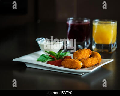 Kindermenü: knusprige Chicken Nuggets mit Tomaten, Basilikum und Sahne-Sauce auf einem weißen Teller Stockfoto