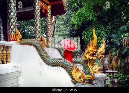 Frau Tourist mit roten traditionelle Thai Regenschirm im Tempel Kloster mit Drachen Statuen in Chiang Mai, Thailand Stockfoto