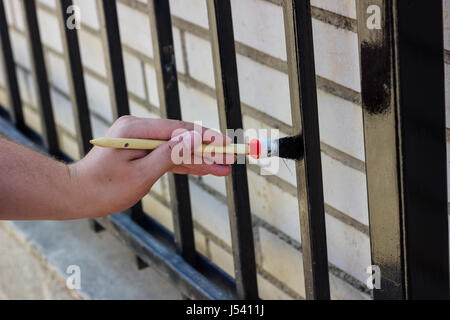 Hand mit Pinsel Malerei Metallzaun Stockfoto