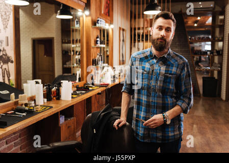 Schön schön Friseur stehen in der Nähe seines Arbeitsplatzes Stockfoto