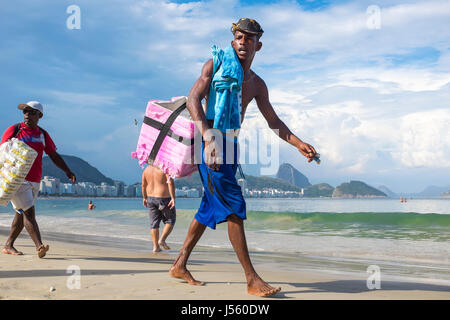 RIO DE JANEIRO - 2. März 2017: Brasilianische Anbieter Strandwanderung entlang der Copacabana Strand verkaufen Getränke und Snacks in behelfsmäßigen Kühler und Taschen getragen. Stockfoto