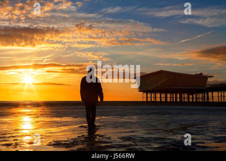 Southport, Merseyside. 16. Mai 2017. Großbritannien Wetter.  Nach einem schweren Regenschauer & böigem Wind geht ein Mann am Strand, einen atemberaubenden Sonnenuntergang zu beobachten, wie sie über Southport Pier in Merseyside ruht.  Bildnachweis: Cernan Elias/Alamy Live-Nachrichten Stockfoto