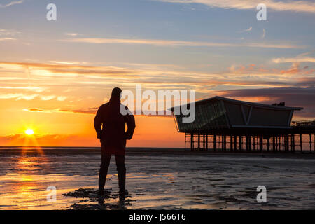 Southport, Merseyside. 16. Mai 2017. Großbritannien Wetter.  Nach einem schweren Regenschauer & böigem Wind geht ein Mann am Strand, einen atemberaubenden Sonnenuntergang zu beobachten, wie sie über Southport Pier in Merseyside ruht.  Bildnachweis: Cernan Elias/Alamy Live-Nachrichten Stockfoto