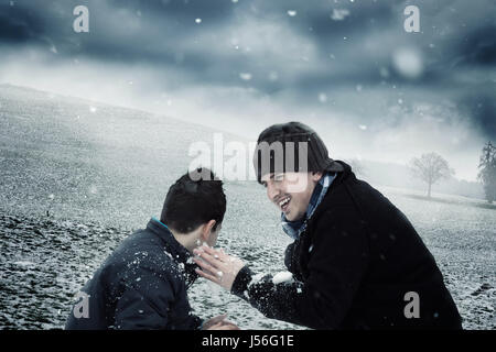 spielerische Mann und Knabe mit Schnee draußen spielen Stockfoto