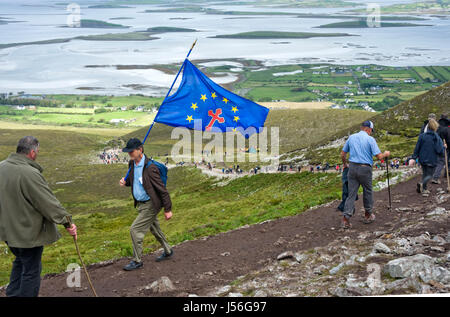 Mann mit christlichen Euro kennzeichnen aufsteigenden Croagh Patrick auf "Reek Sunday" Stockfoto