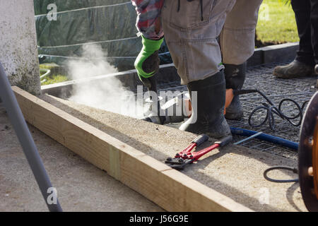 Handwerker mit Bohrhammer draußen im Garten, Bohrung Stockfoto