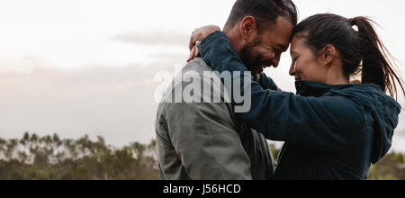 Horizontalen Schuss junges Paar in Liebe zusammen im Freien stehen. Romantischer junger Mann und Frau in Landschaft umarmen. Stockfoto