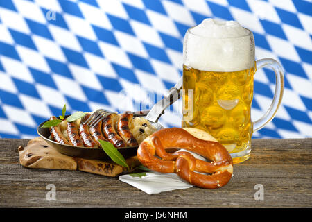 Gebratene Nürnberger Würstchen auf Sauerkraut mit einem Becher bayerisches Bier und Brezel Stockfoto