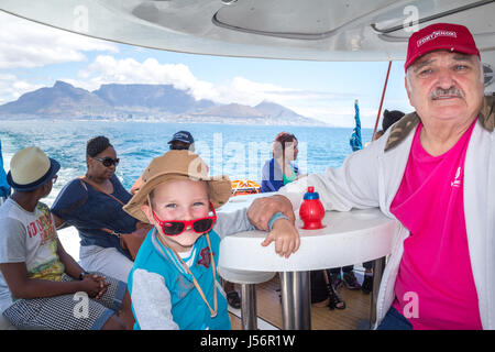 CAPE TOWN, SOUTH AFRICA, 18. Dezember 2016: begeistert kleine Junge und Großvater auf Fähre verlassen Table Bay mit dem Tafelberg im Hintergrund zu Ro Stockfoto