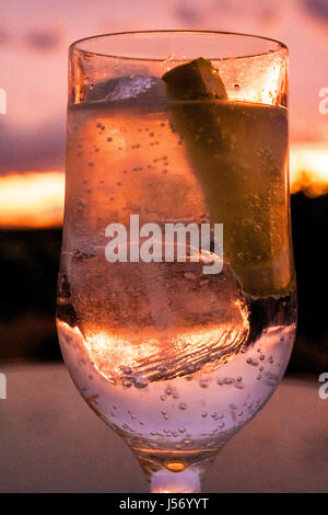 Glas-Drink mit Eis und Zitrone bei Sonnenuntergang Stockfoto