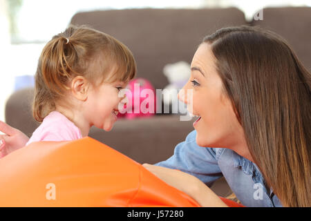Seite Ansicht Porträt einer glücklichen Mutter und 2 Jahre Baby Tochter konfrontiert und scherzen im Wohnzimmer zu Hause Stockfoto