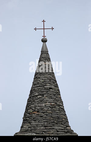 Eisen-Kreuz auf alten Kirchturm gebaut mit Granitblöcken gegen blauen Himmel Stockfoto
