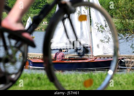 Eine junge Frau fährt rund um den See Aasee in Münster (Deutschland), während ein Seemann sein Segelschiff, 23. April 2011 vorbereitet. | weltweite Nutzung Stockfoto