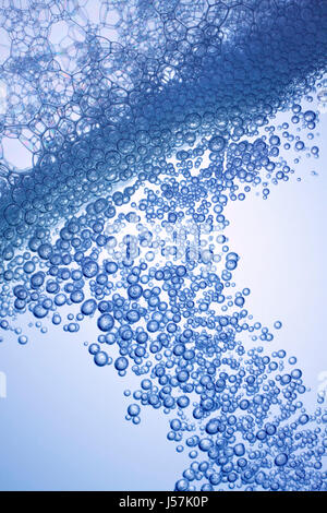 Wasserlinie mit dichten Luftblasen und seifigen Luftblasen. Hintergrundbeleuchtung, blaue Tönung, schrägen Gestell. Stockfoto