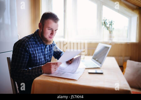 Gut aussehender Mann einige Papiere zu Hause zu tun. Stockfoto