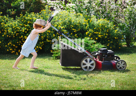 kleine niedlicher junge mäht Rasen mit Mäher Stockfoto