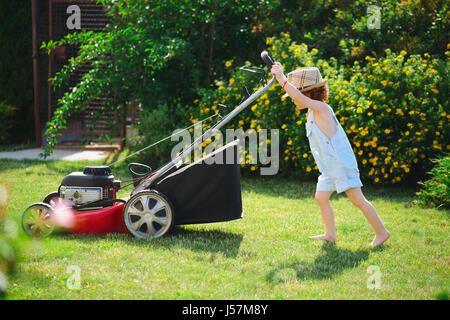 kleine niedlicher junge mäht Rasen mit Mäher Stockfoto