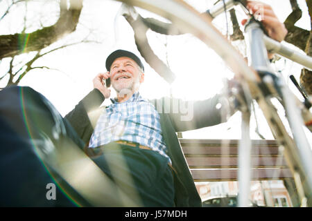 Senior Mann mit Fahrrad und Smartphone-Anruf tätigen Stockfoto