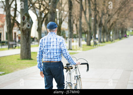 Senior woman in blau kariertes Hemd mit dem Fahrrad in der Stadt. Stockfoto