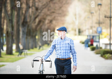 Senior woman in blau kariertes Hemd mit dem Fahrrad in der Stadt. Stockfoto