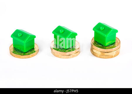 Grüne Häuser sitting on Top of Stapel von Münzen, auf einem weißen Hintergrund. Stockfoto