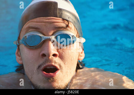 Schwimmer-Gesicht auf blauem Wasser Pool Hintergrund. Junger Mann Kopf im Poolwasser Stockfoto