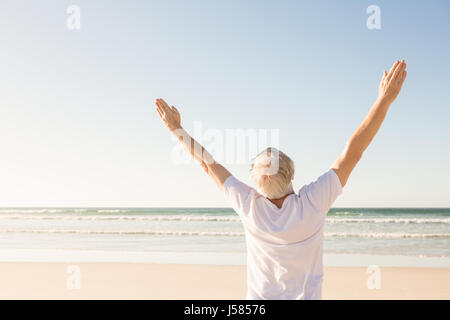 Ansicht der Rückseite des älteren Mann mit erhobenen Armen stehen am Strand Stockfoto