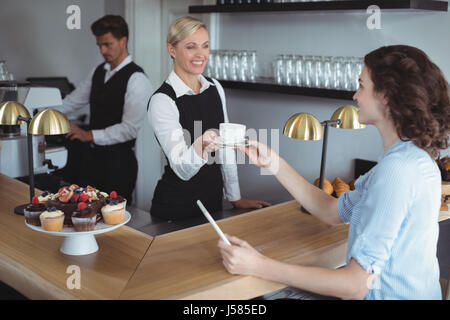 Kellnerin, die Kunden am Schalter im Restaurant Kaffee anzubieten Stockfoto