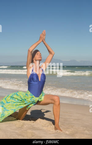 Frau mit Armen hob Praktizierenden Yoga gegen klaren Himmel am Strand Stockfoto