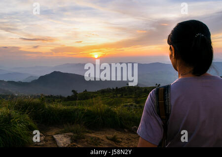 Frau Touristen auf der Suche schöne Natur des bunten Himmel während des Sonnenuntergangs über dem Berg am Aussichtspunkt Phu Chi Fa Forest Park in der Provinz Chiang Rai Stockfoto