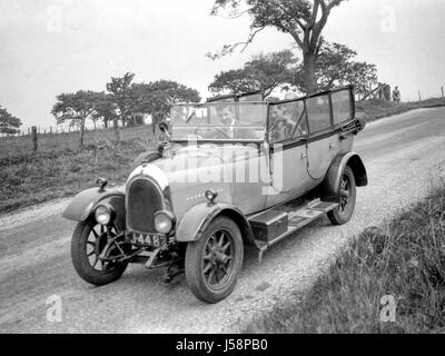 Eine Gruppe von Menschen, für eine Fahrt in einem 11.9hp Bean vier Tür Cabrio im Jahr 1926 erbaut und zunächst auf der Insel Bute, Scotland registriert. Zwei Männer sind in den Vordersitzen, der Passagier ist im Besitz einer Golftasche und eine Dame ist auf dem Rücksitz. An der Spitze des Bildes ist ein Radfahrer um die Ecke kommen. Die Aufnahme wurde im Jahre 1931. Mit einen hochauflösenden Scan genommen von der ursprünglichen negativen wiederhergestellt. Stockfoto