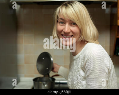 Junge blonde Frau hält einen Topf oben mit einem Lächeln auf ihrem schönen Gesicht Stockfoto