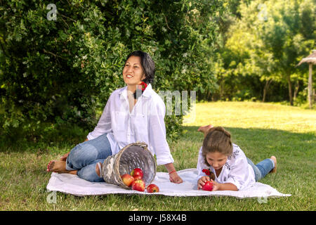Bild Mutter und Tochter im Park auf dem Rasen mit Apfelkorb Stockfoto