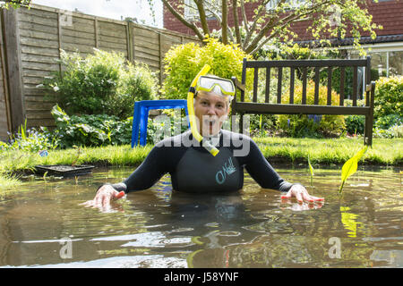 Reife Frau mit Spaß tragen Anzug, Brille, Schnorchel, im kleinen Gartenteich, Teichpflanzen bewegen. Haben Sie einen lachen. Nur so zum Spaß. Als ein Witz. VEREINIGTES KÖNIGREICH. Stockfoto