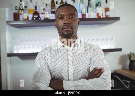 Porträt von bar tender Stand mit verschränkten am Tresen im restaurant Stockfoto