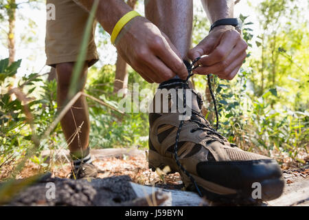 Mann binden Bootlaces im Wald an einem sonnigen Tag Stockfoto