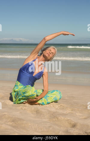 Nahaufnahme von Frau Yoga praktizieren, sitzend auf Sand am Strand Stockfoto