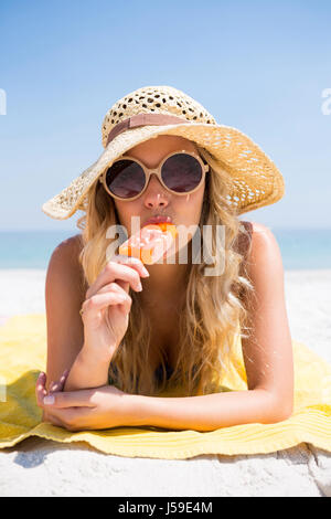 Porträt der jungen Frau essen Eis am Stiel auf sonnigen Tag am Strand entspannen Stockfoto