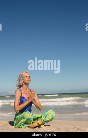 Nahaufnahme von Frau sitzend am Ufer gegen klaren Himmel am Strand meditieren Stockfoto